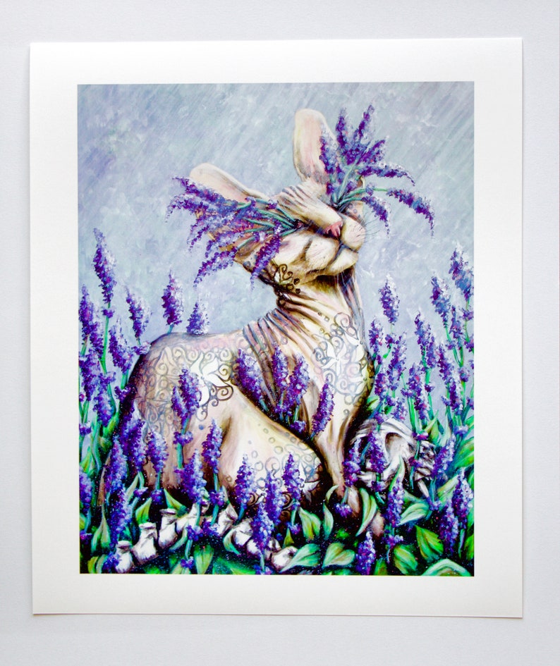 K&ouml;nnte beinhalten: Eine wei&szlig;e haarlose Katze mit einem floralen Tattoo sitzt in einem Feld mit lila Lavendelbl&uuml;ten. Die Augen der Katze sind geschlossen und die Blumen bedecken ihren Kopf.