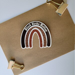May include: A brown and black rainbow sticker with the text "Black Births Matter" in white lettering.