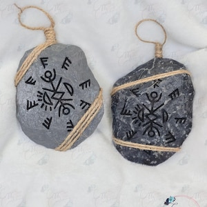 May include: Two gray stone ornaments with a black geometric design and wrapped in twine. The ornaments are hanging from a twine loop.