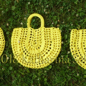 May include: Three handmade yellow crochet tote bags with handles are displayed on a bed of green grass. The bags have a circular design with open weave patterns. The bags are in different sizes. The text "2018 Katharina Sekirua" is visible.