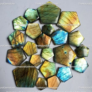 May include: A collection of 16 iridescent labradorite gemstone cabochons in various shades of green, blue, and gold. The cabochons are cut in a hexagonal shape and have a smooth, polished finish.