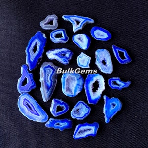 May include: A collection of 18 blue agate slices with natural crystal formations and a white interior. The agate slices are arranged in a circle on a black background. The text "BulkGems" is visible in the center of the image.