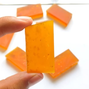 Könnte beinhalten: Fünf rechteckige Stücke durchscheinender orangefarbener Süßigkeiten mit einer körnigen Textur.