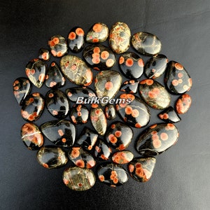 May include: A collection of 20 black and red gemstone cabochons with a speckled pattern. The stones are oval and teardrop shaped.