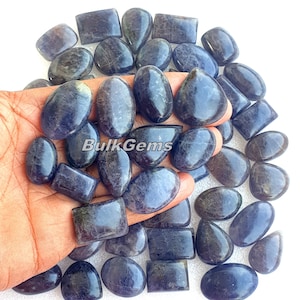 May include: A collection of 30 blue-grey gemstone cabochons in various shapes, including oval, teardrop, and rectangular. The stones are smooth and polished, with a subtle shimmer.