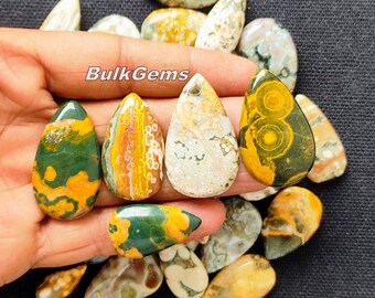 May include: A collection of 15 teardrop-shaped, polished, green, yellow, and white ocean jasper stones. The stones are approximately 1 inch in length and have a variety of patterns and colors.