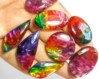 May include: A collection of eight iridescent gemstone cabochons in various shapes and sizes. The stones display a rainbow of colors, including red, orange, yellow, green, blue, and purple.