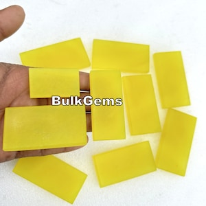Puede incluir: Diez piezas rectangulares de citrino pulido de color amarillo. El citrino es translúcido y tiene un ligero aspecto esmerilado. BulkGems está impreso sobre un fondo blanco.