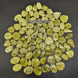 Pode incluir: Uma coleção de cabochões de pedra preciosa verde e preta salpicada em forma de lágrima. As pedras são polidas e têm um acabamento liso e brilhante.