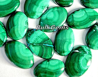 Puede incluir: Una colección de cabujones de malaquita de forma ovalada, cada uno con patrones únicos verdes y blancos. Las piedras son lisas y pulidas, mostrando la belleza natural del mineral.