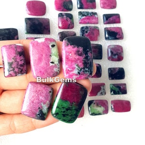 Op de afbeelding: Een verzameling van 20 roze, groene en zwarte edelsteen cabochons. De cabochons zijn rechthoekig en hebben een gladde, gepolijste afwerking. De cabochons zijn gerangschikt in rijen op een wit oppervlak. De tekst "BulkGems" is zichtbaar in de afbeelding.