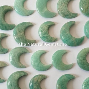 Può includere: Una collezione di pietre verdi a forma di mezzaluna. Le pietre sono lisce e levigate, con un aspetto naturale e terroso. Il testo "The Natural Gemstone" è stampato sull'immagine.