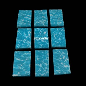 May include: Nine rectangular turquoise gemstones with a white, marbled pattern. The gemstones are arranged in a grid against a black background. The text "BULKGEMS" is visible on one of the gemstones.