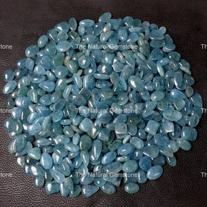 Puede incluir: Un montón grande de piedras preciosas de aguamarina azul claro, todas facetadas y pulidas. Las piedras son de varias formas y tamaños, algunas son ovaladas y otras más redondeadas. Las piedras están dispuestas en un montón suelto sobre un fondo oscuro.