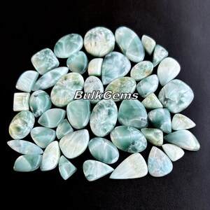 May include: A collection of 30 green and white cabochon gemstones. The stones are various shapes and sizes, including oval, teardrop, and square. The stones are polished and have a smooth, shiny finish.