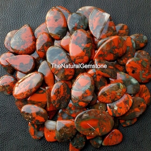 May include: A collection of 30 natural red and black jasper cabochons. The cabochons are oval and teardrop shaped and have a variety of patterns and colors. The cabochons are perfect for jewelry making or other craft projects.