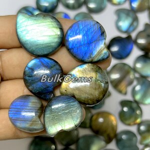 May include: A collection of Labradorite gemstone cabochons in various shades of blue, green, and gold. The stones are smooth and polished, with a pearlescent sheen.