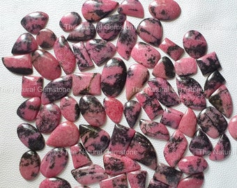 May include: A collection of 40 pink and black natural gemstone cabochons. The stones are various shapes and sizes, including oval, teardrop, and rectangular. The stones are polished and have a smooth, glossy finish.