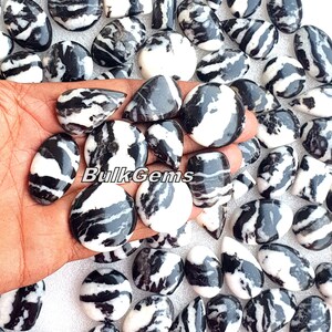 May include: A collection of black and white zebra jasper cabochons, a type of gemstone known for its distinctive striped pattern. The cabochons are smooth and polished, with a variety of shapes and sizes.
