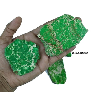 Pode incluir: Close-up de pedras de jaspe verde com veios brancos e castanhos. As pedras têm uma textura natural e áspera. A imagem inclui o texto "BULKGEMS" no canto inferior direito.