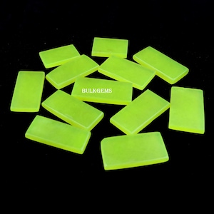 May include: A collection of 10 bright yellow-green rectangular cabochons, likely gemstones, arranged on a black background. The cabochons are smooth and polished, with a slight sheen. The text "BULK GEMS" is visible in the centre of the image.