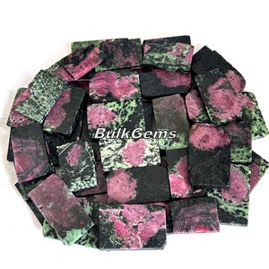 May include: A collection of green, pink, and black gemstone chips. The chips are rectangular and have a rough, natural finish. BulkGems is printed on the chips.