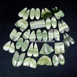May include: A collection of 25 green and white banded agate gemstone cabochons in various shapes, including oval, teardrop, and heart shapes. TheNaturalGemstone is printed on the image.