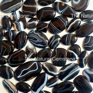 May include: A collection of black and white banded agate cabochons. The stones have a natural, polished finish and are ideal for jewellery making.
