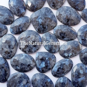 May include: A collection of 20 faceted, oval-shaped, blue labradorite gemstones. The stones have a dark blue colour with a shimmery, iridescent effect.