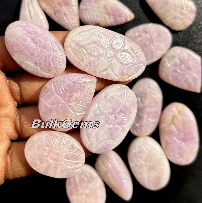 May include: A collection of 15 pink carved gemstone cabochons with floral designs. The cabochons are smooth and polished, with a delicate pink hue. The carvings are intricate and detailed, showcasing the beauty of the natural gemstone.