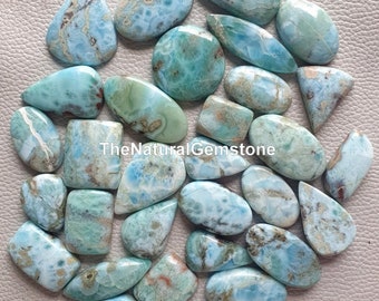 Könnte beinhalten: Eine Sammlung von 25 natürlichen blauen und grünen Edelstein-Cabochons. Die Cabochons haben verschiedene Formen und Größen und ein marmoriertes Muster. TheNaturalGemstone ist auf dem Bild gedruckt.