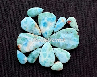 Könnte beinhalten: Eine Sammlung von 11 blauen und weißen Edelstein-Cabochons in Tropfenform. Die Steine haben ein einzigartiges, marmoriertes Muster und sind in einem Kreis auf schwarzem Hintergrund angeordnet. BulkGems ist in weißer Schrift auf dem Bild gedruckt.