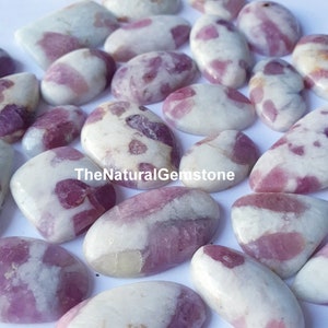 Puede incluir: Una colección de 18 cabujones ovalados, cada uno con un patrón único de rosa y blanco. Las piedras son lisas y pulidas, con un aspecto natural y orgánico. TheNaturalGemstone está impreso en la imagen.