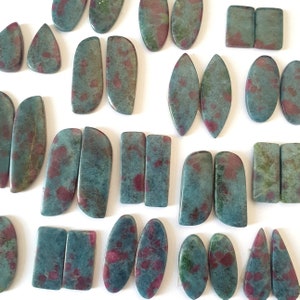 Puede incluir: Una colección de 18 cabujones de piedras preciosas verdes y rojas, algunos ovalados, algunos rectangulares y algunos en forma de lágrima. Las piedras están pulidas y listas para la elaboración de joyas.