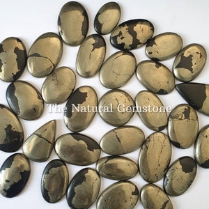 Op de afbeelding: Een verzameling van 20 ovale pyriet cabochons met een goud en zwart kleurpatroon. De stenen zijn glad en gepolijst, met een natuurlijke, aardse uitstraling.