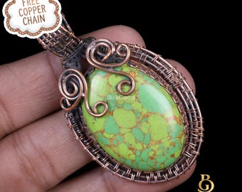 May include: A handcrafted pendant featuring a vibrant green gemstone with brown veining, encased in copper wire. The wirework includes decorative swirls and an oval frame. The pendant is labeled "BulkGems" and includes a "Free Copper Chain" tag.