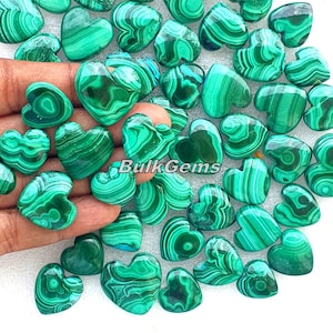 Könnte beinhalten: Eine Sammlung herzförmiger Malachit-Edelsteine. Die Steine zeigen eine leuchtend grüne Farbe mit komplizierten Wirbelmustern. Das Bild enthält den Text "Bulk Gems".