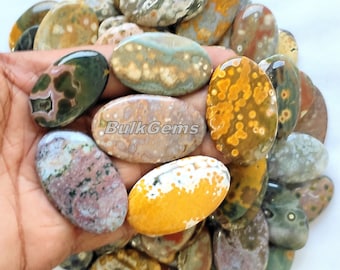 May include: A collection of oval-shaped, polished ocean jasper stones in various shades of green, brown, yellow, and white. The stones have a unique, swirling pattern and are perfect for jewelry making or decorative purposes.