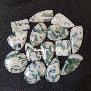 May include: A collection of 14 moss agate cabochons in various shapes and sizes. The stones are a mix of white and green with a swirling pattern.