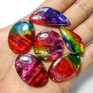 May include: Six iridescent gemstone cabochons in various shapes and sizes, displaying a rainbow of colours including red, orange, yellow, green, blue, and purple.