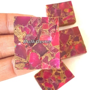 May include: Close-up of several square-shaped gemstones with a mosaic pattern. The stones feature a mix of deep red, magenta, and gold colors. The text "Bulk Gems" is visible on one of the stones.