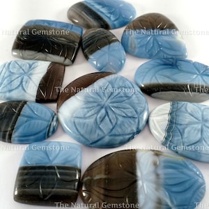 Puede incluir: Una colección de diez cabochones de ópalo tallados en tonos azules, blancos y marrones. Los cabochones están tallados con un diseño floral y tienen un acabado liso y pulido.