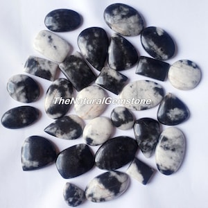 May include: A collection of 25 black and white gemstone cabochons. The stones are various shapes and sizes, with a swirling pattern of black and white.