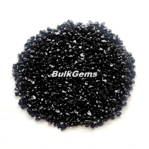 May include: A close-up of a pile of black obsidian chips. The chips are small and irregular in shape, and they have a shiny, glassy finish.