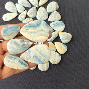 May include: A collection of blue and white banded agate cabochons in a teardrop shape. The cabochons are polished and have a smooth, glossy finish.
