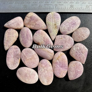 May include: A collection of 15 pink carved gemstone cabochons with leaf and flower designs. The cabochons are various shapes and sizes. The text "Bulk Gems" is visible in the image.