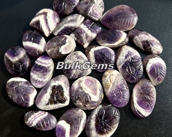 May include: A collection of 20 amethyst gemstone cabochons, each carved with a leaf design. The cabochons are a mix of purple and white, with some having a more pronounced white band.