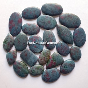 May include: A collection of 20 green and pink ruby zoisite cabochons. The stones are oval and teardrop shaped and have a speckled pattern.