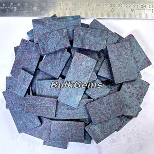 May include: A pile of blue and red gemstone cabochons. The cabochons are irregularly shaped and have a mottled appearance. The text "Bulk Gems" is visible in the image.