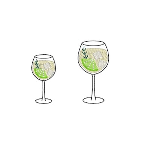 May include: Two embroidered wine glasses, one smaller than the other, each filled with a cocktail. The drinks feature ice cubes, a lime wedge, and sprigs of greenery. The glasses have thin stems and are set against a white background.